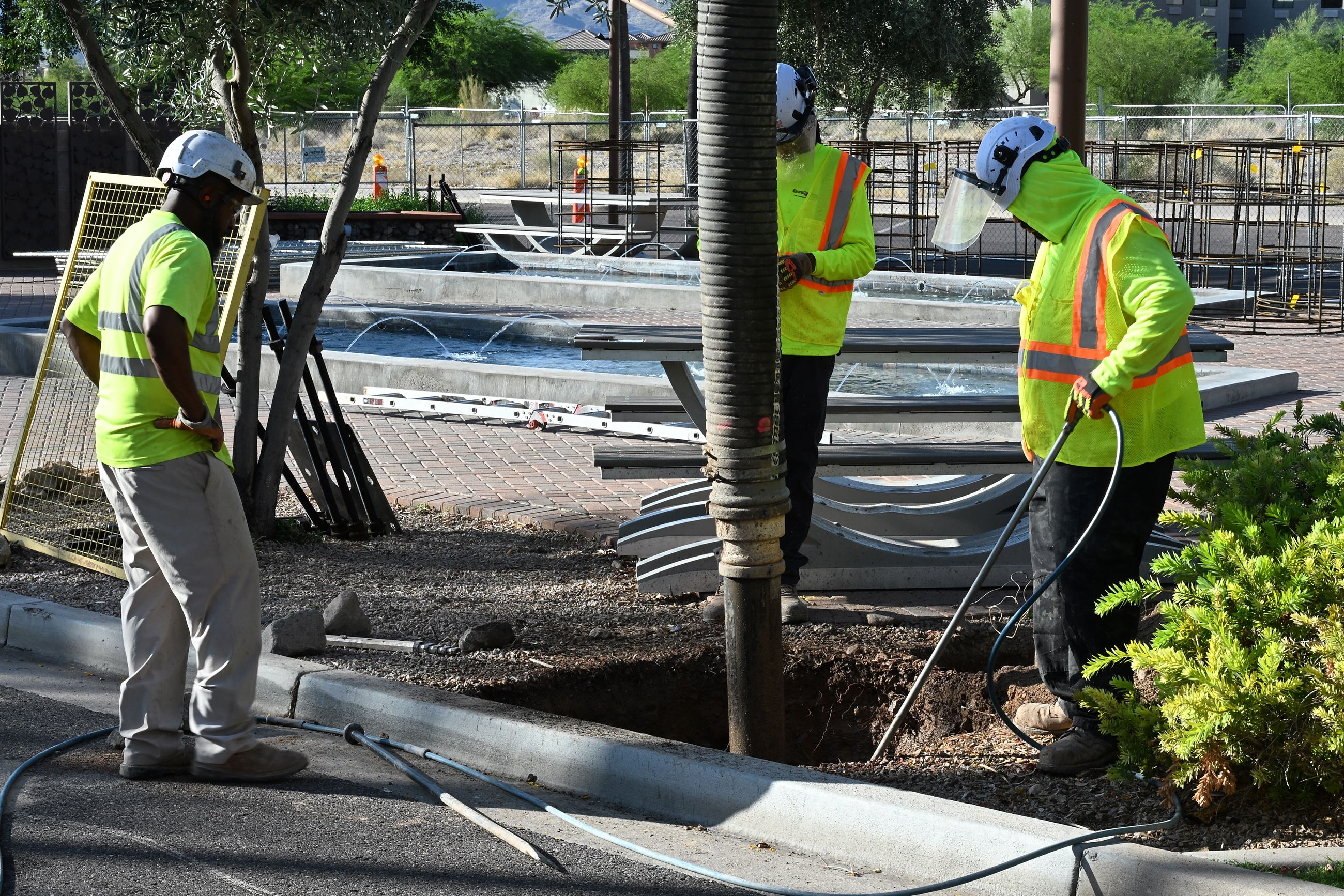 Crews working on digging holes for shade structure